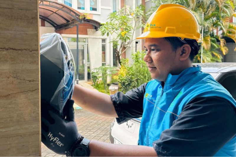 Ilustrasi petugas PLN saat melakukan pemasangan home charger di rumah pelanggan untuk memudahkan pengisian kendaraan listrik di rumah.